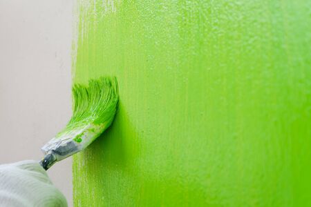 Close up brush painting green color on wall - green coloringの写真素材