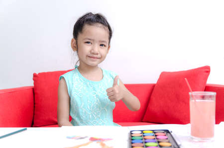Asian little girl showing thumb up and play water color