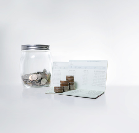 Stack of coins on saving bank accound book on the white background with copy space, Selective focus...