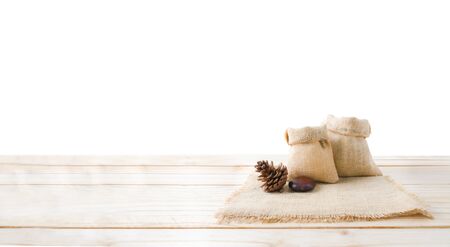 Two of blank hemp sack bag and pine cones on wood table top floor isolated on white background with...