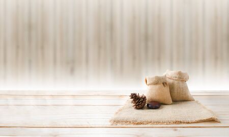 Two of blank hemp sack bag and pine cones on wood table top floor over blur wood background with copy spaceの写真素材
