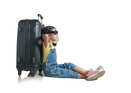 Asian little girl close her eyes for relaxing and sitting lean the luggage with happiness isolated on white background with clipping path, concept for travelの写真素材