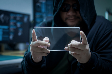 Hacker using blank clear glass tablet with blue dark and grain process concept for cyber technology data and network hacking criminalの写真素材