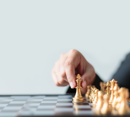 Close up shot hand of business woman moving golden chess to defeat a silver king chess on white and black chess board for business challenge competition winner and loser concept with copy space, selective focus on king chess shallow depth of fieldの写真素材