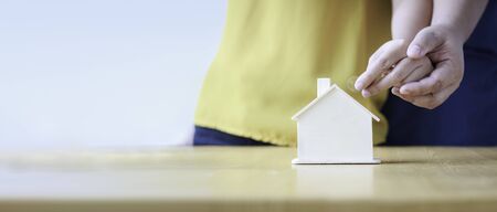 Close up shot hands of man and woman putting the coin to house piggy bank ratio for web banner and header design metaphor and concept for Couple saving money for buy home and real estate select focus on handの写真素材