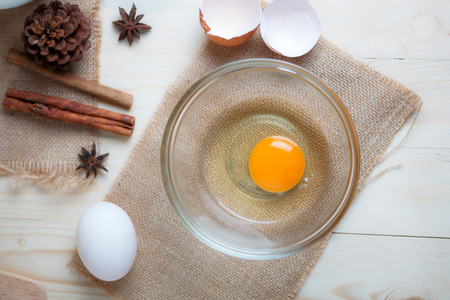 Egg on clear glass bowl over wooden cut board with bakery ingredients select focus shallow depth of...