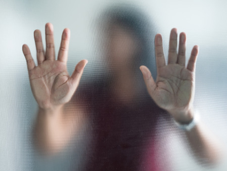 Blurry woman hand behind frosted glass metaphor panic and negative dark emotionalの写真素材
