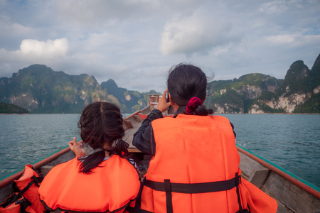 Mother and daughter tourist against scenic landscape of boat view in the big river and reservoir dam with mountain and nature forestの写真素材