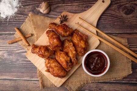 Hot and spicy Korean barbeque fried chicken on wood cutting board over wooden table preparing for meal and tastyの写真素材