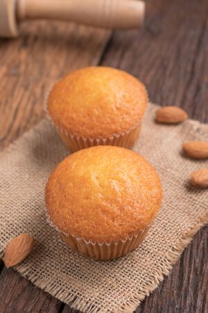 Close up a cup of almond cake against sack fabric on wooden table, select focus shallow depth of fieldの写真素材