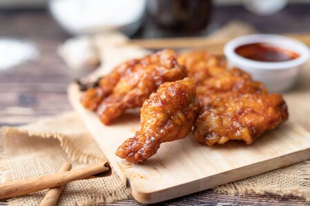 Hot and spicy Korean barbeque fried chicken on wood cutting board over wooden table preparing for meal and tastyの写真素材