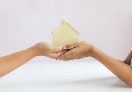 Hand of mother giving the wooden house model to daughter metaphor the legacy of real estate concept select focus shallow depth of fieldの写真素材