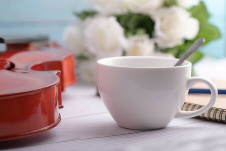 Close-up shot coffee cup and violin orchestra instrumental over white wooden background select focus shallow depth of fieldの写真素材
