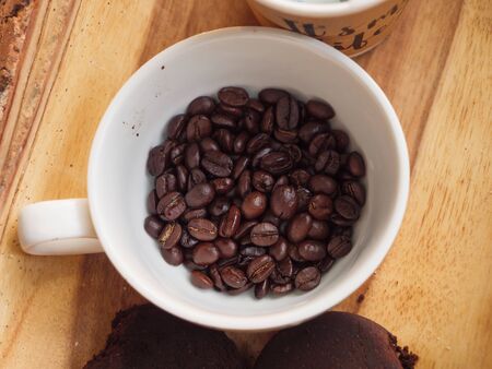 Close-up shot a group of roasted coffee bean in the white cup against wooden table select focus shallow depth of fieldの写真素材