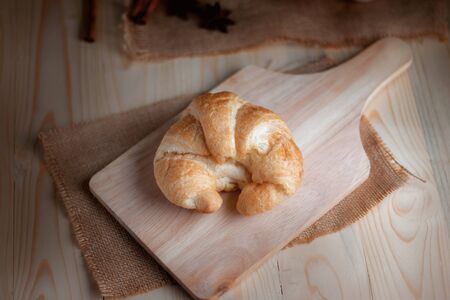 Croissant on wooden cut board on table wood and fabric select focus shallow depth of field の写真素材