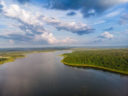 Drone shot aerial view scenic landscape a big river with fresh green tree forest and mountain against a blue skyの写真素材