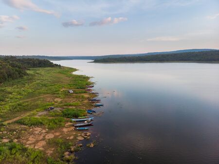 Drone shot aerial view scenic landscape the fishing boat in a big river with fresh green tree and beachの写真素材