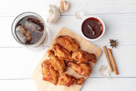 Hot and spicy Korean barbeque fried chicken on wood cutting board over wooden table preparing for meal and tastyの写真素材