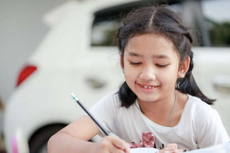 Portrait of a Little Asian girl in Thai student uniform is hugging her Persian cat with happiness,...
