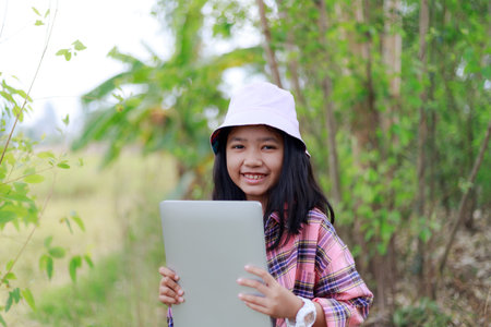 The little Asian girl holding tablet at the tropical farm, Little famer smile with happinessの写真素材