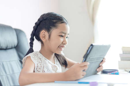 Little Asian girl using tablet and smile with happiness for education concept select focus shallow depth of fieldの写真素材