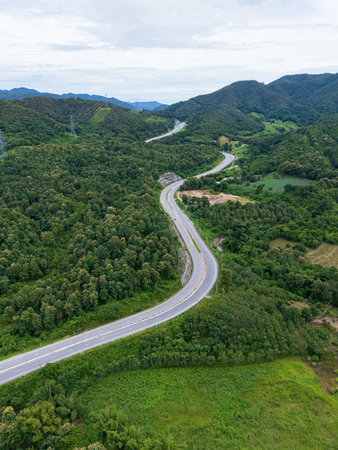 Aerial drone view of Highway 101 winding through lush green mountains between Phrae and Nan,...