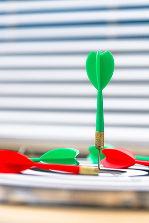 Green dart hitting the bullseye while red darts miss the target, symbolizing business competition, strategic advantage, leadership, and successful decision-making in a competitive marketの写真素材