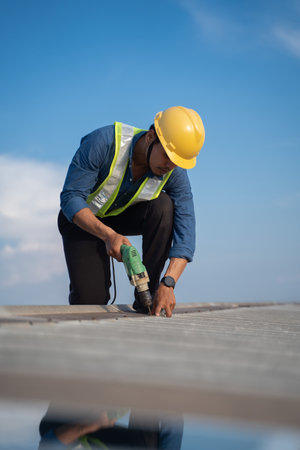 Worker repairing the roof on a construction site. Electric drill used on roof, Roof construction...