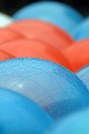 Shot of several balloons, red, blue, and white floating in a pool.  The balloons were used as...