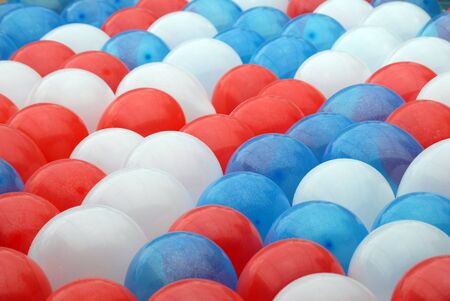 Shot of several balloons, red, blue, and white floating in a pool.  The balloons were used as decoration on 4th of July.の写真素材