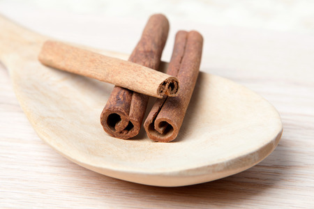 Cinnamon sticks on a wooden spoon on a wood plank