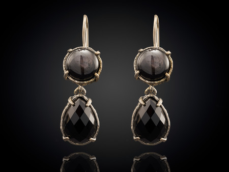 Golden earrings with gemstone isolated on black background.の写真素材