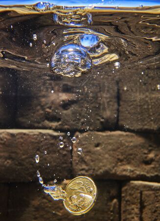 euro coin falling in a whising well.の写真素材