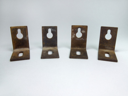 The metal corners for hanging cabinets, with holes for screws. Rustyの写真素材