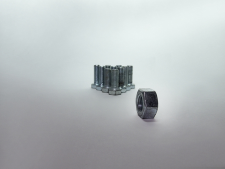 Bolts, arranged in a pyramid like bowling pins and nut in front of them, like a bowling ballの写真素材