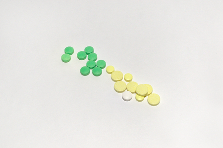streak of green and yellow pills and a white pelletの写真素材