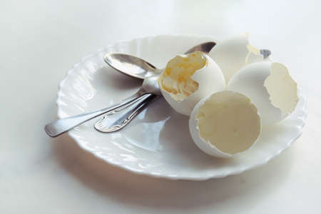 ending of morning meal of soft-boiled eggs in elegant plate, with three teaspoons on it