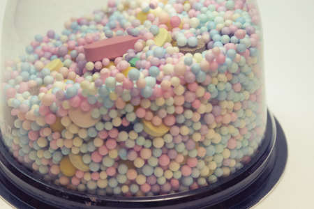 medicine pills, tablets and multicolored small round vitamin dragees closeup under plastic...