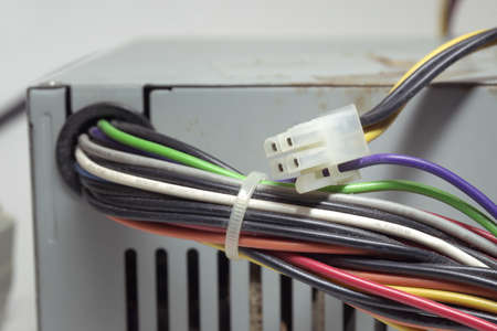 computer ATX non-modular power supply unit front side. outdated power connectors of PC drives and mainboard. power connectors for drives, tied with a plastic white cable tieの写真素材