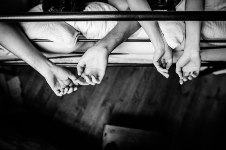 Hands of a pair which is on the bed. Black and white photo, top viewの写真素材