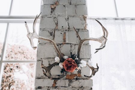 Antlers with flower hanging on a white brick wall near the window. Decor, vintage, modern, loftの写真素材