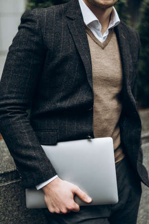 Laptop in the hands of a stylish man in a suitの写真素材
