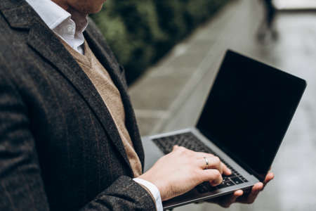 Image on which stylish man is holding a laptop outdoor. A laptop with clean screen and space for...