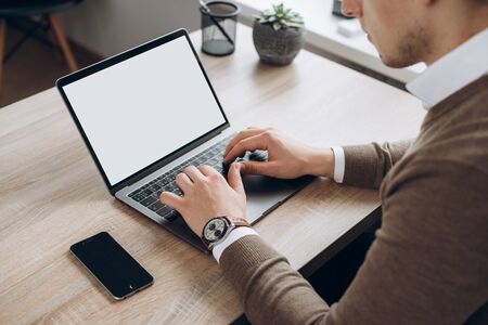 Male hands on laptop keyboard. A laptop with a clean white screen and blank space for text. Side...