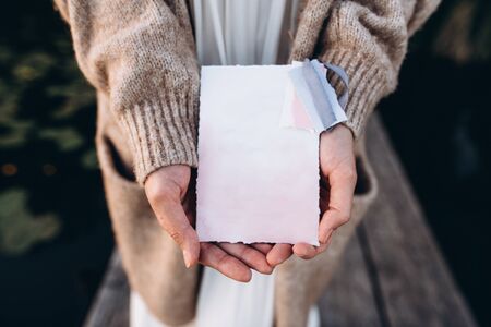 The girl is holding an invitation in pastel colors with an empty space for text. Top viewの写真素材