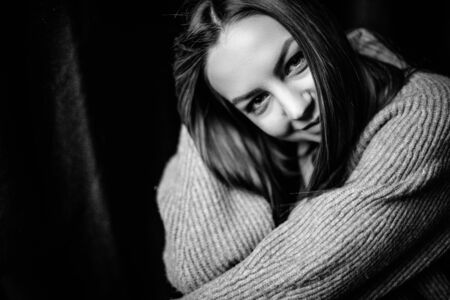 Emotional and atmospheric black and white portrait of a beautiful girl with long hair and charismatic smile on a black backgroundの写真素材