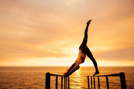 A girl practices yoga by the sea during a beautiful sunset. Fitness and healthy lifestyle