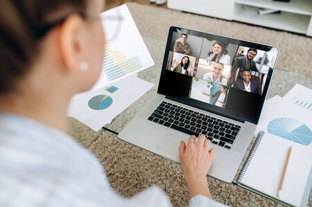 Business team working from home in a video conference. The back view of a girl who communicates...