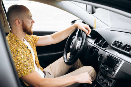 Concentrated bearded man driving his favorite comfortable car, he looks on the roadの写真素材