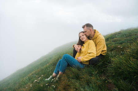 Love in the mountains. A loving couple of Caucasian ethnicity hugging while sitting on the top of the mountain, enjoying each other, the landscape and harmonyの写真素材